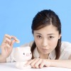 女性が貯金箱にお金を入れようとしている