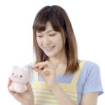貯金箱にお金を入れる女性